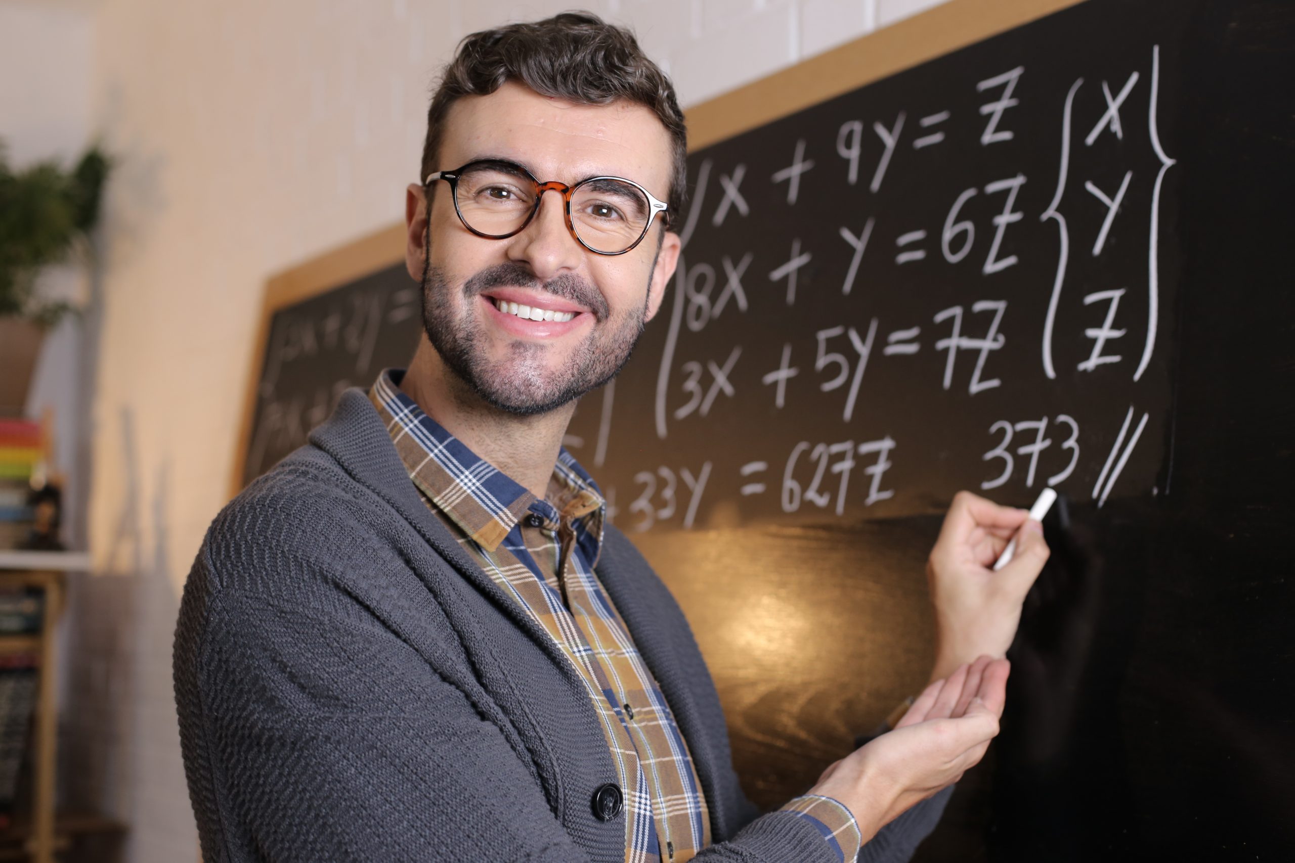 Math teacher writing with chalk in classroom.